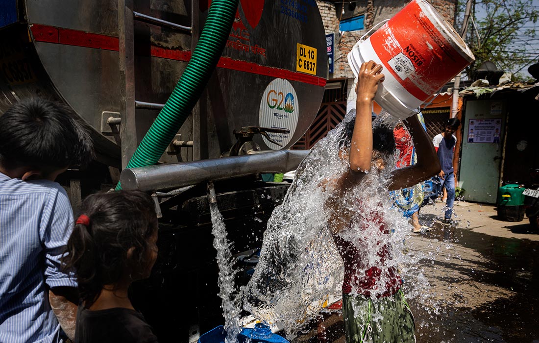 Мальчик охлаждается водой из цистерны в Нью-Дели