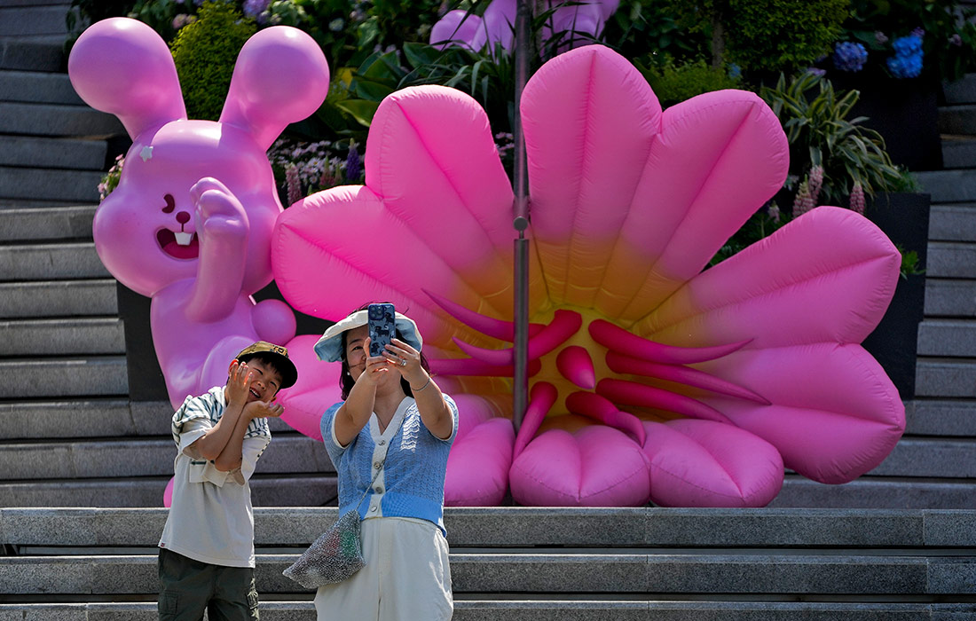 Женщина с ребенком фотографируются возле надувных фигур цветов в Пекине