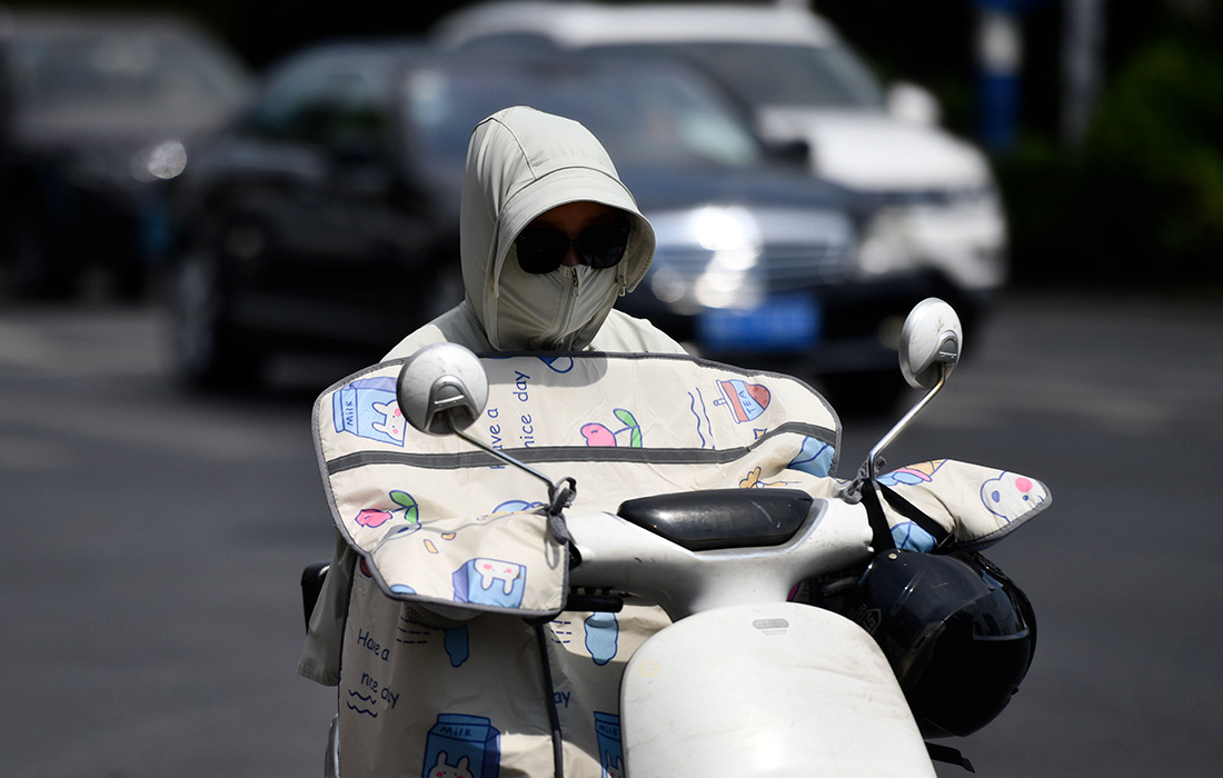 Оранжевое предупреждение о высокой температуре в Китае. На фото: граждане носят солнцезащитную одежду в городе Фуян.