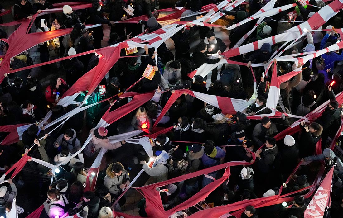 Протестующие рвут флаг партии "Сила народа" во время митинга с требованием импичмента южнокорейскому президенту