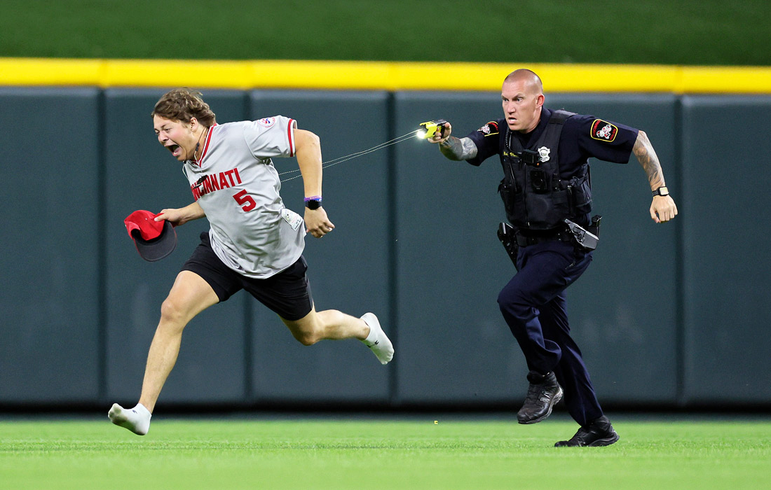 Полицейский стреляет электрошокером в выбежавшего на поле болельщика на бейсбольном матче между командами "Цинциннати Редс" и "Кливленд Гардианс", штат Огайо, США