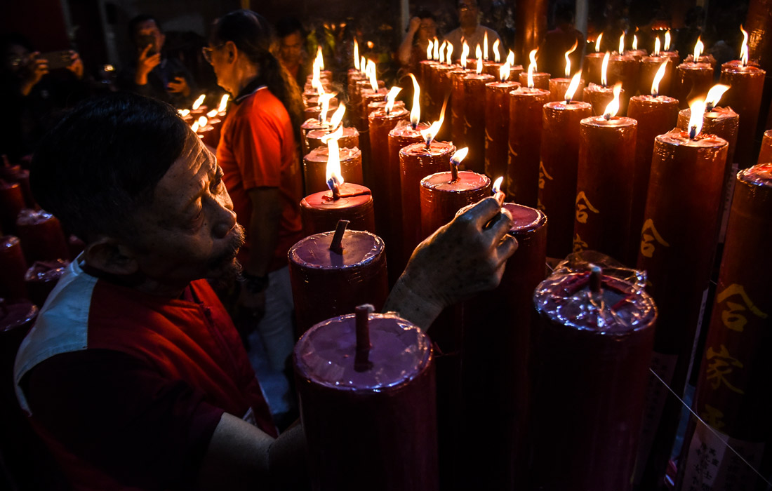 Мужчина зажигает свечи в храме Дхарма Рамси на острове Ява, Индонезия