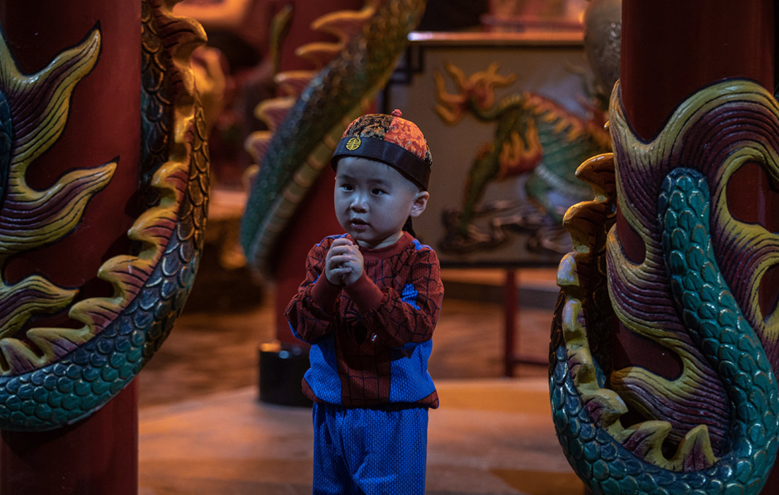 Мальчик возносит молитвы в храме в Джакарте, Индонезия