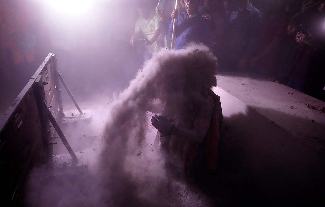 Индуистский святой совершает омовение пеплом в деревне Джхуласан, Индия