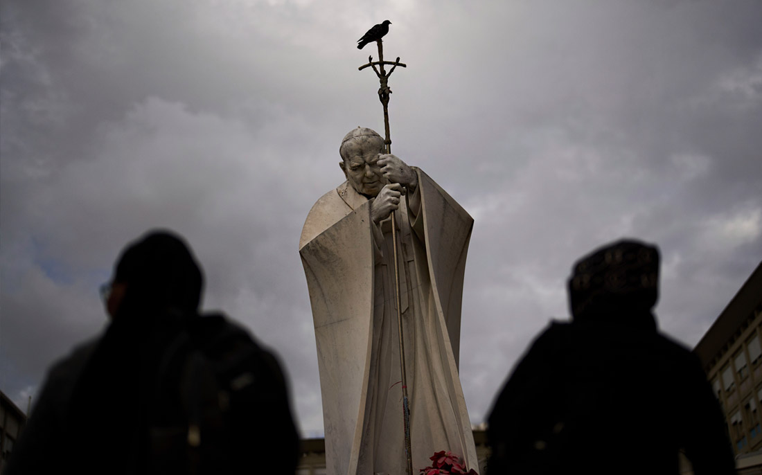 В Ватикане сообщили о небольшом улучшении состояния папы римского. На фото: верующие у статуи папы Иоанна Павла II напротив клиники, где понтифик проходит лечение.