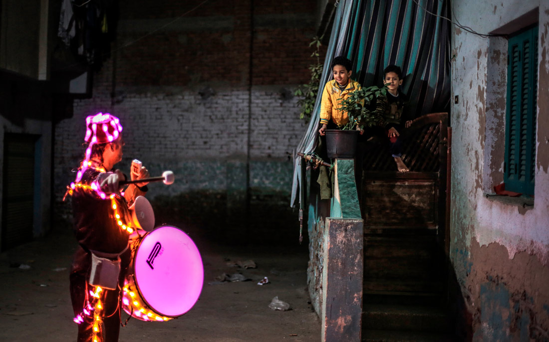 Барабанщик приглашает соседей на вечернюю трапезу во время Рамадана на севере Каира, Египет