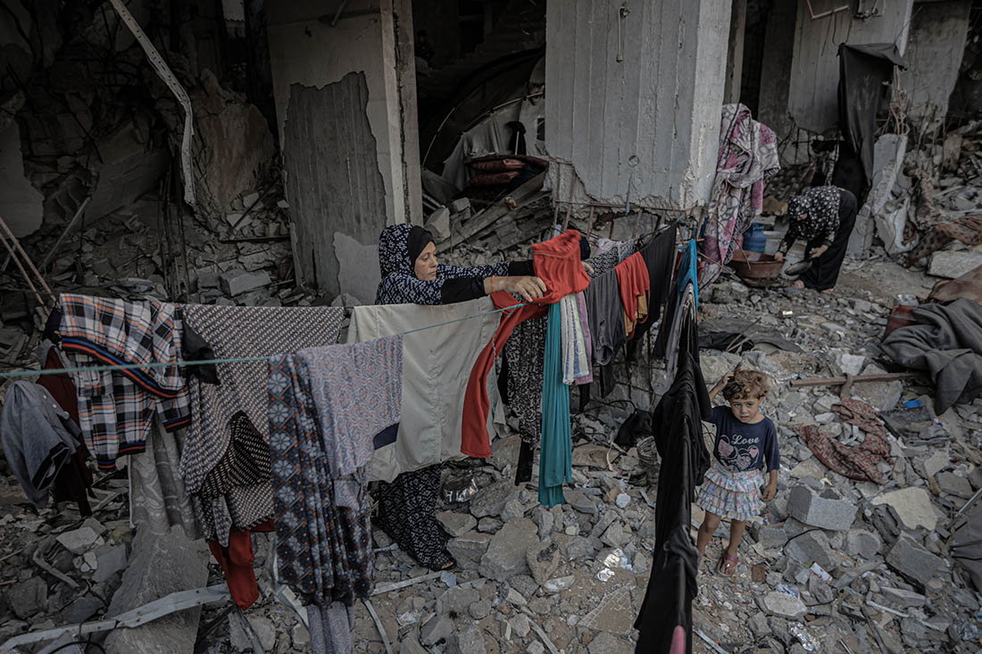 Женщина развешивает одежду для сушки в Газе