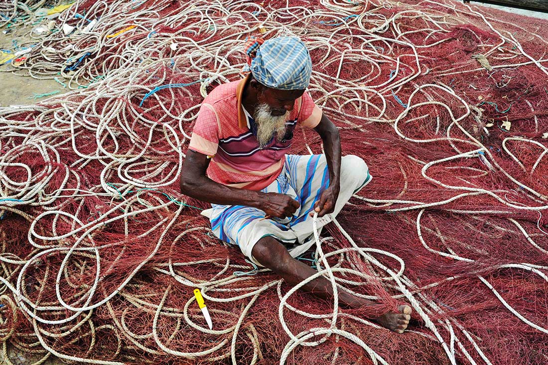 Мужчина плетет сети для ловли рыбы гильзы в Бангладеш
