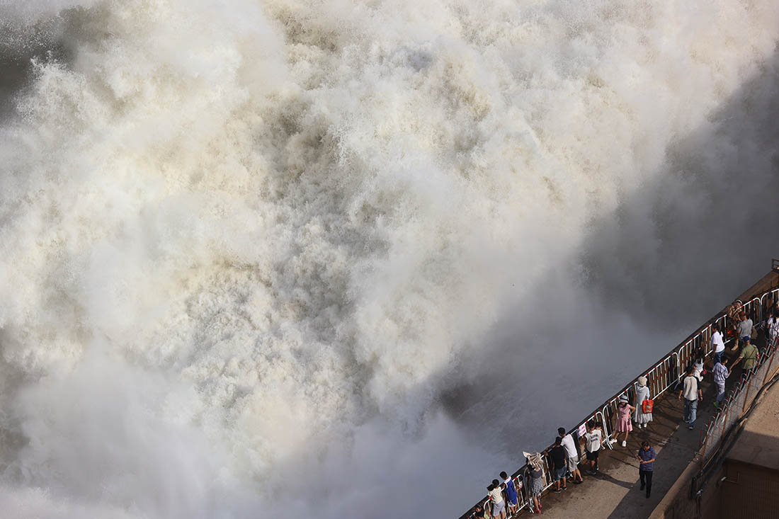 Люди наблюдают за сбросом воды из водохранилища на Желтой реке в Китае