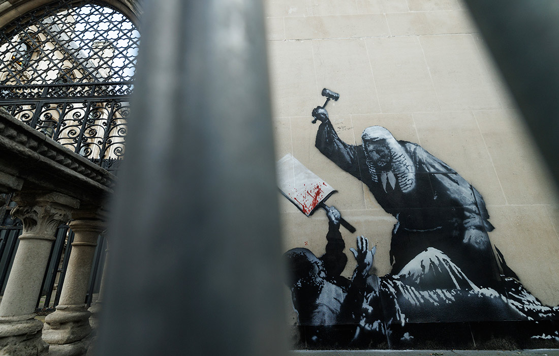 Работа Бэнкси на стене Королевского суда, изображающая судью, избивающего протестующего. Через несколько часов она была скрыта и взята под охрану сотрудниками службы безопасности.