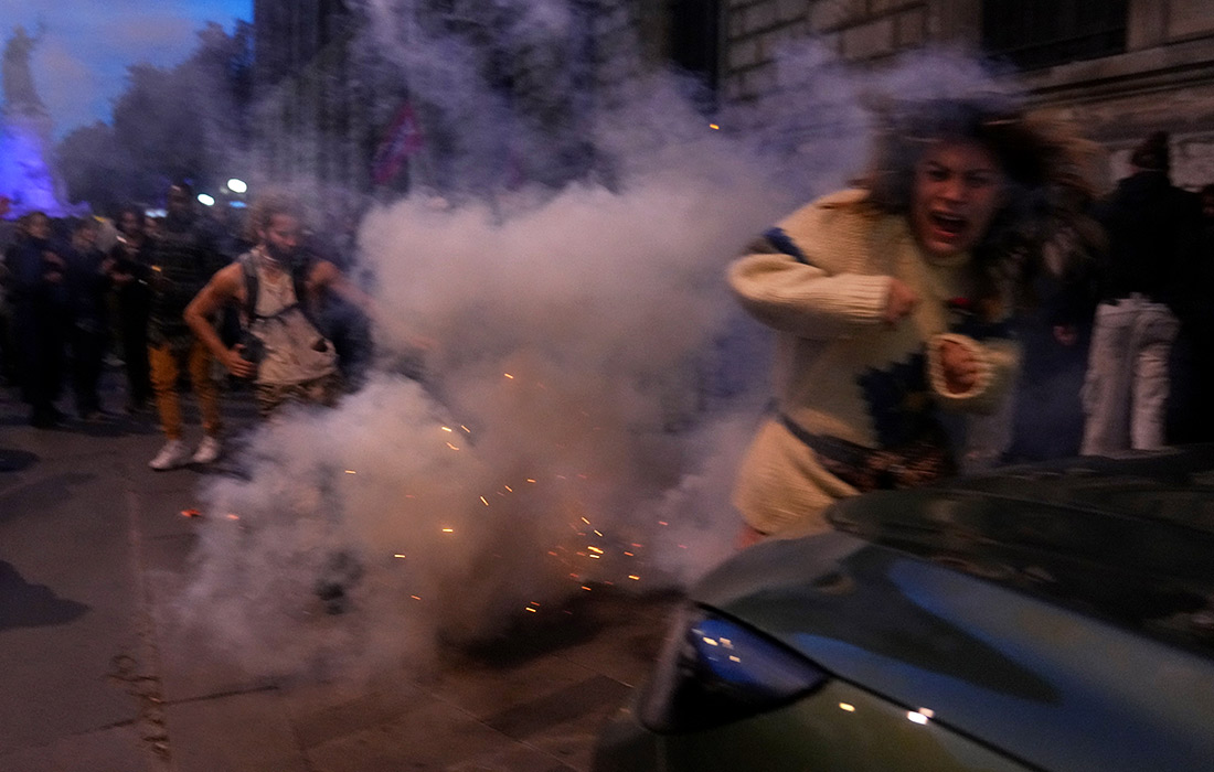 Протестующий пытается уклониться от слезоточивого газа в Париже во время демонстрации после того, как флотилия судов с гуманитарной помощью, направлявшаяся в Газу, была перехвачена Армией обороны Израиля