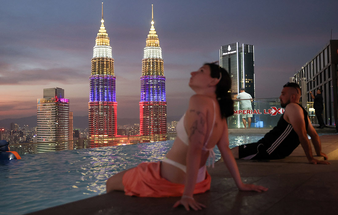 Люди у бассейна с видом на башни Петронас в Куала-Лумпуре