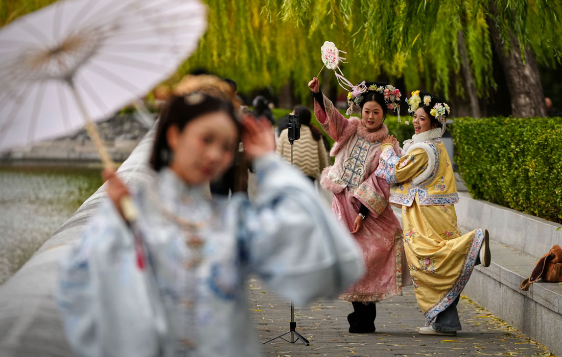 Девушки в традиционных нарядах фотографируются возле Запретного города в Пекине