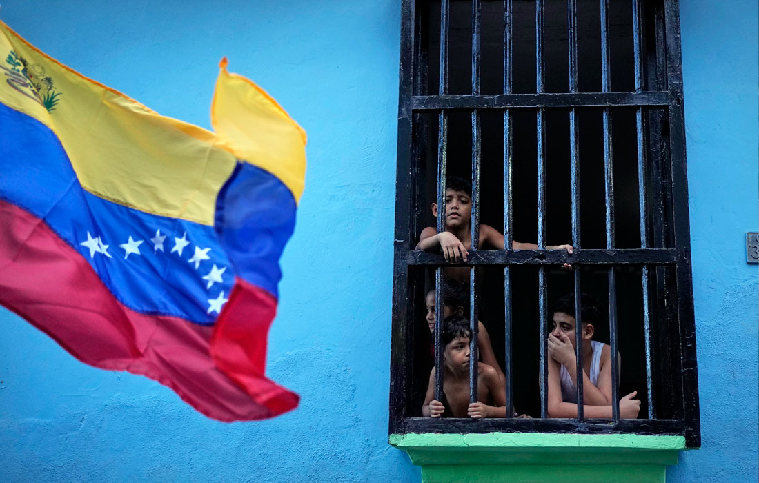 Дети смотрят из окна на марш сторонников правительства, требующих освобождения президента Николаса Мадуро и его жены в Ла-Гуайре на севере Венесуэлы