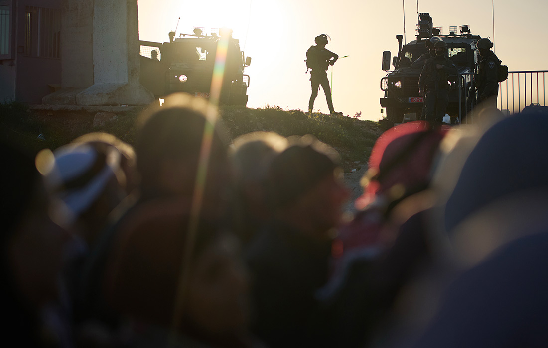 Израильские солдаты стоят на страже, наблюдая, как палестинские верующие проходят через КПП по пути на пятничную молитву в мечеть Аль-Акса