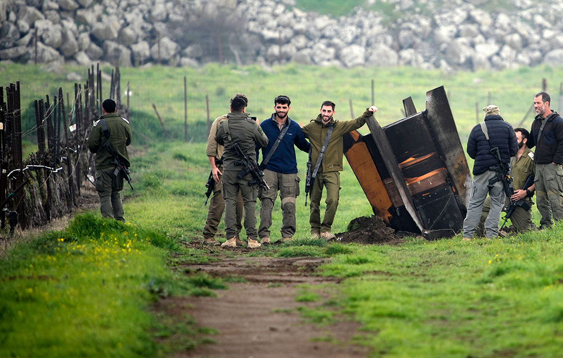 Израильские солдаты фотографируются рядом с фрагментом ракеты, выпущенной с территории Ирана