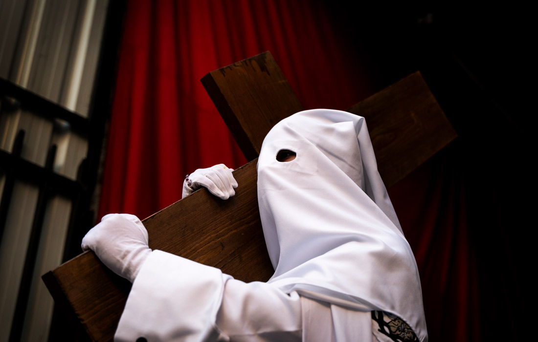 Кающийся грешник из братства Lealtad y Despojado принимает участие в религиозном шествии в Касересе, Испания