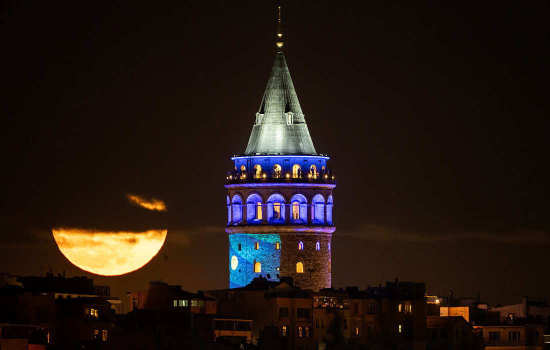 Полная луна восходит за Галатской башней в Стамбуле