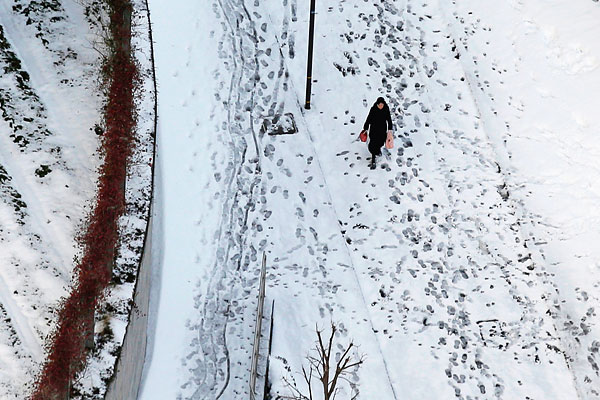 Женщина идет по заснеженной улице в Токио