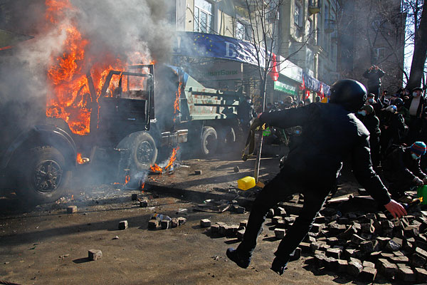 Антиправительственные демонстранты бросают камни и  бутылки с зажигательной смесью во время атаки на офис Партии регионов.