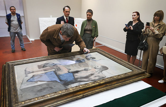 Эксперт осматривает картину "Девочка на шаре" Пабло Пикассо