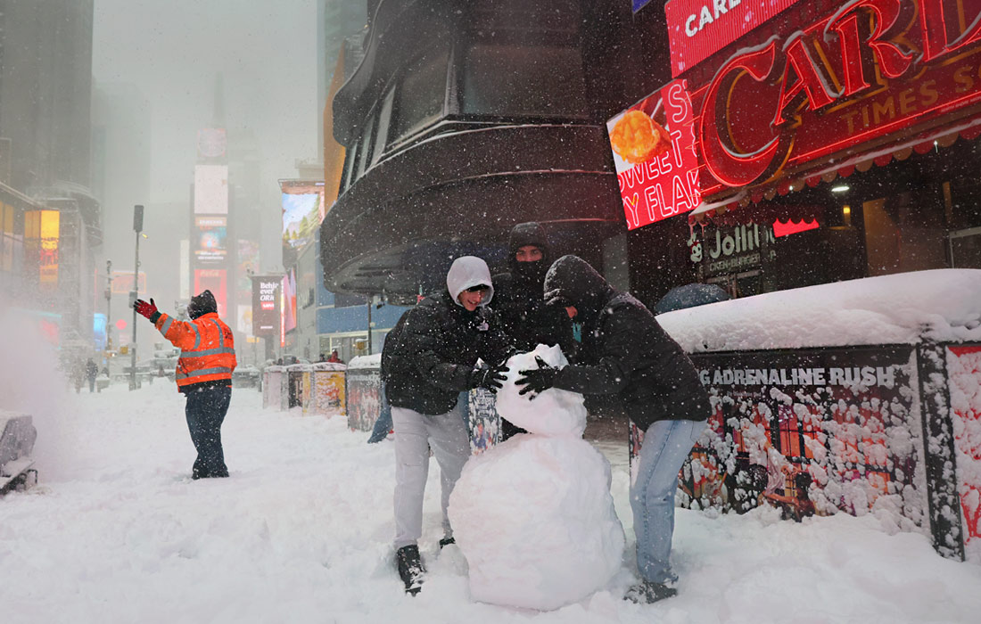 Жители Нью-Йорка лепят снеговика на Таймс-Сквер во время метели
